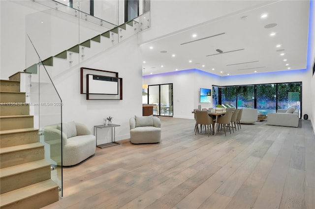 interior space featuring recessed lighting, wood-type flooring, a towering ceiling, stairway, and baseboards