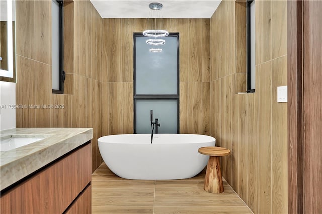 bathroom featuring a freestanding tub, vanity, and tile walls