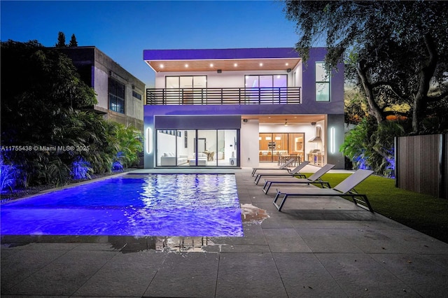 rear view of property with a balcony, a patio area, a fenced in pool, and stucco siding