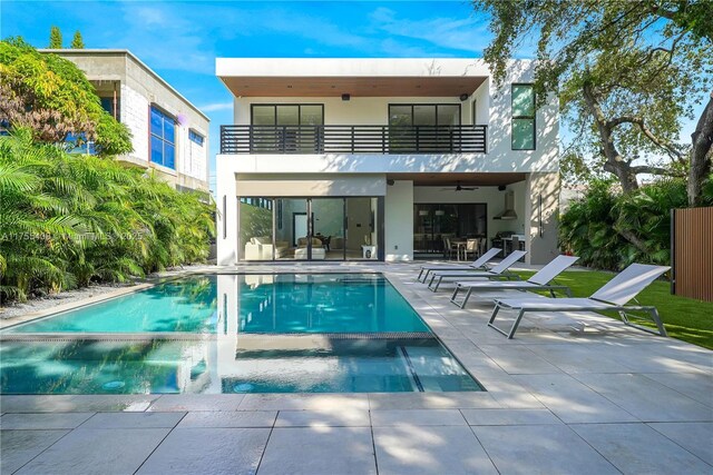 rear view of property featuring a patio, a pool with connected hot tub, a balcony, and stucco siding