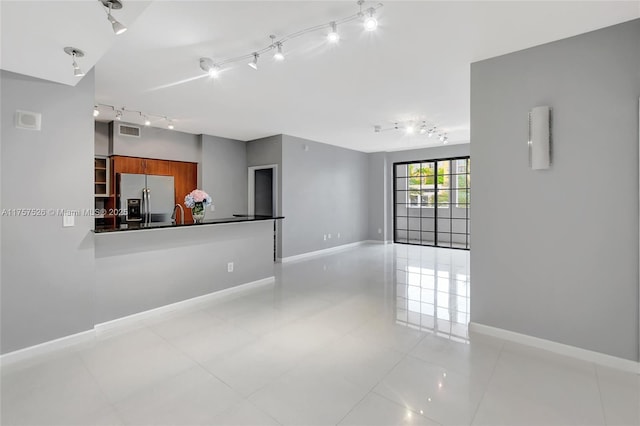 unfurnished living room featuring light tile patterned floors, a sink, visible vents, baseboards, and track lighting