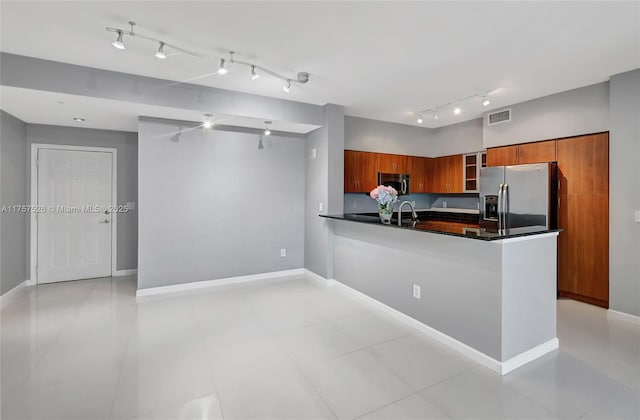 kitchen with brown cabinets, dark countertops, visible vents, appliances with stainless steel finishes, and a peninsula