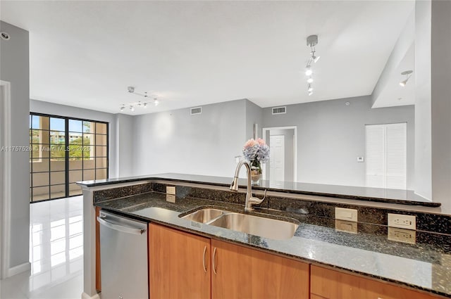 kitchen featuring a sink, open floor plan, stainless steel dishwasher, brown cabinets, and dark stone counters