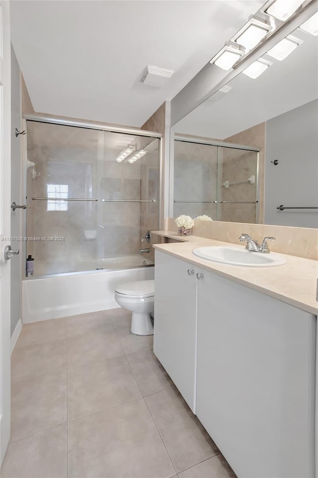 bathroom featuring vanity, bath / shower combo with glass door, tile patterned flooring, and toilet