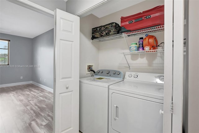 clothes washing area featuring laundry area, baseboards, wood finished floors, and washing machine and clothes dryer