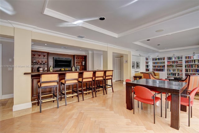 dining area featuring ornamental molding, a tray ceiling, visible vents, and a dry bar