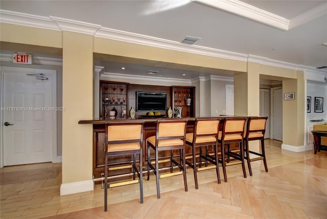 bar with a community bar, visible vents, crown molding, and baseboards