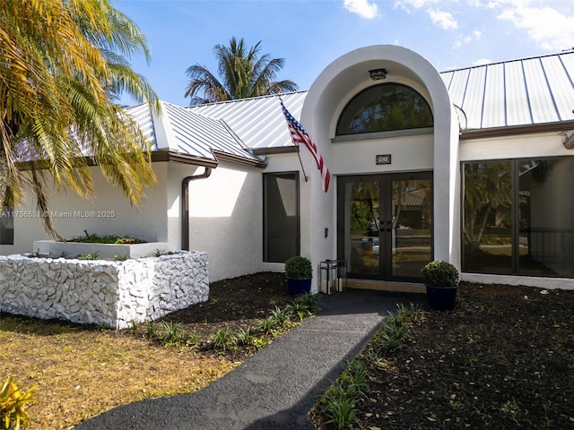 property entrance featuring stucco siding, a standing seam roof, metal roof, and french doors