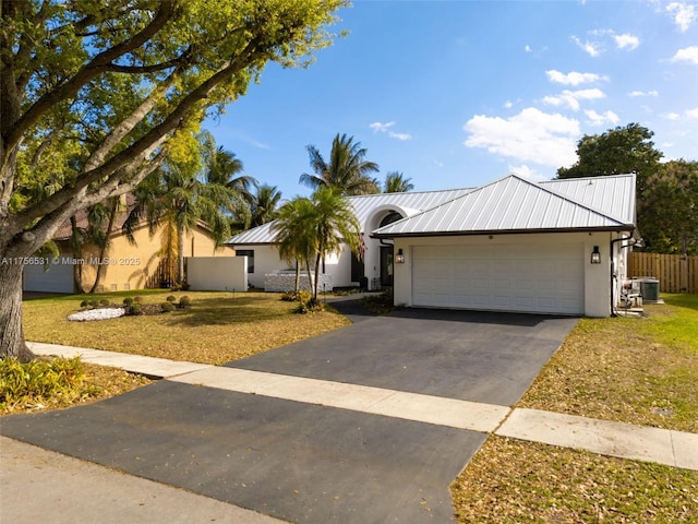 view of front of house featuring a garage, aphalt driveway, metal roof, and stucco siding