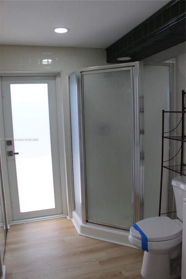 bathroom featuring a stall shower, wood finished floors, and toilet