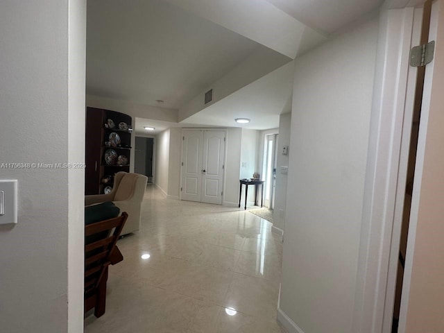 hallway with light tile patterned floors, visible vents, and baseboards