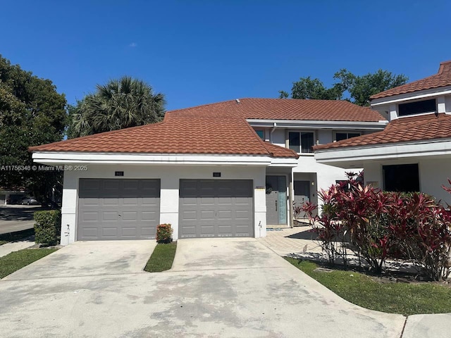 view of front of house with a tiled roof, a garage, driveway, and stucco siding