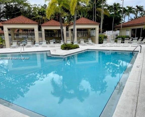 community pool with a gazebo, a patio area, and fence