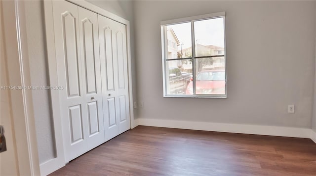 unfurnished bedroom with a closet, wood finished floors, and baseboards