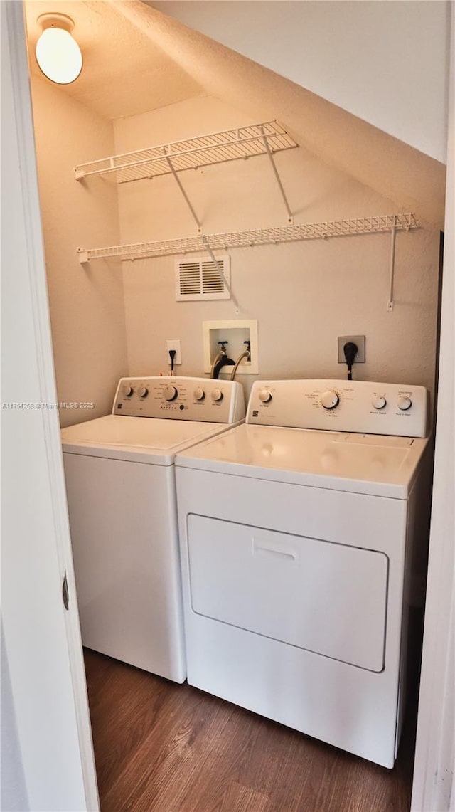 clothes washing area with visible vents, dark wood-type flooring, and independent washer and dryer