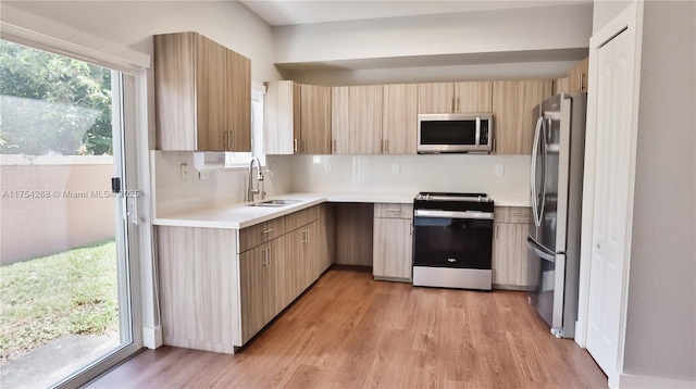 kitchen featuring light wood-style flooring, stainless steel appliances, a sink, and light countertops