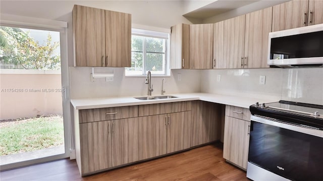 kitchen with light countertops, light wood-style flooring, decorative backsplash, appliances with stainless steel finishes, and a sink