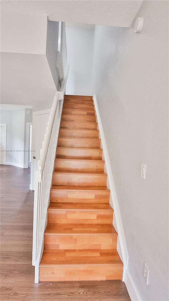 stairs featuring wood finished floors and baseboards