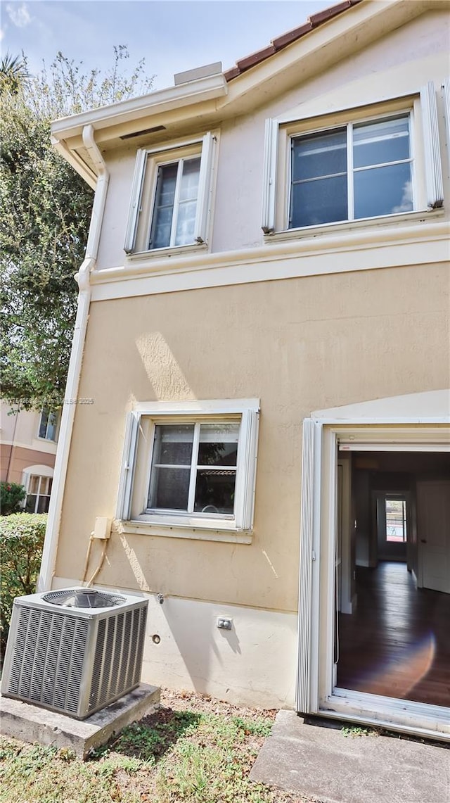 doorway to property featuring central AC unit and stucco siding