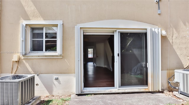 view of exterior entry with stucco siding and central AC unit