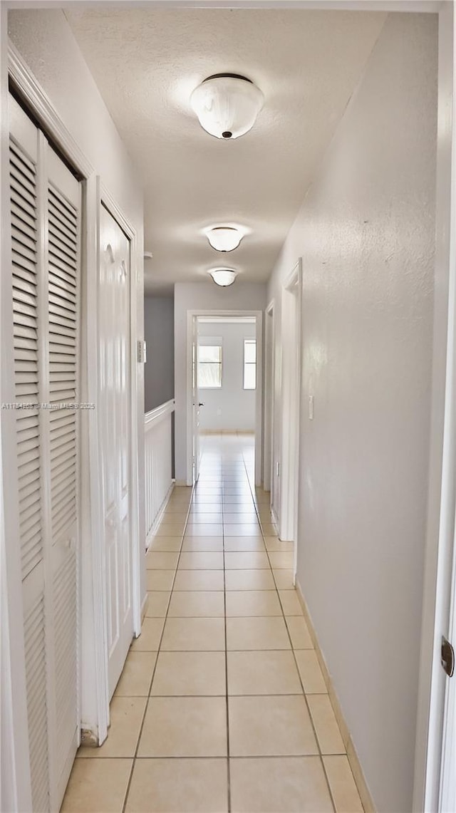 hall featuring light tile patterned floors and a textured ceiling