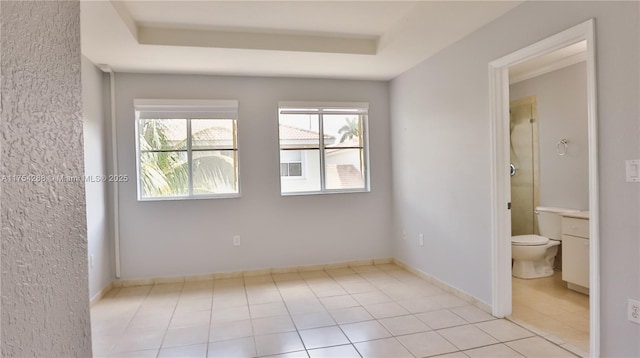 spare room featuring light tile patterned floors, baseboards, and a tray ceiling