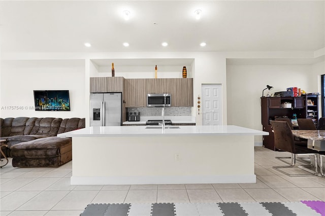 kitchen featuring stainless steel appliances, light tile patterned floors, light countertops, and tasteful backsplash