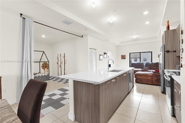 kitchen featuring visible vents, appliances with stainless steel finishes, open floor plan, light countertops, and a sink