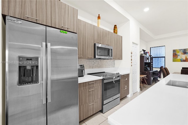 kitchen featuring light tile patterned floors, stainless steel appliances, tasteful backsplash, light countertops, and modern cabinets