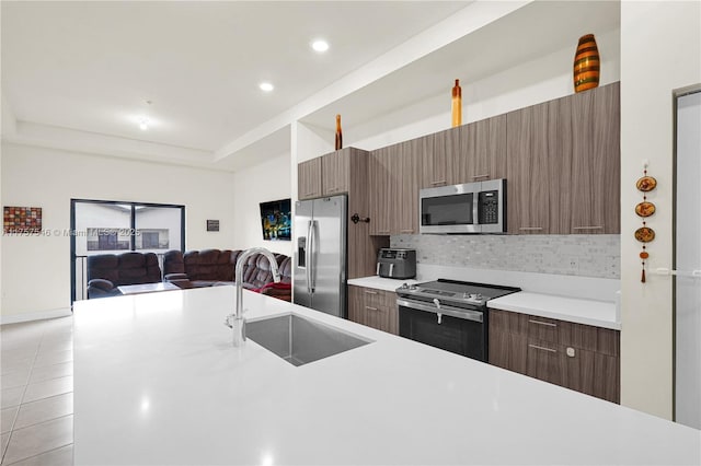 kitchen with light tile patterned flooring, a sink, light countertops, appliances with stainless steel finishes, and a raised ceiling