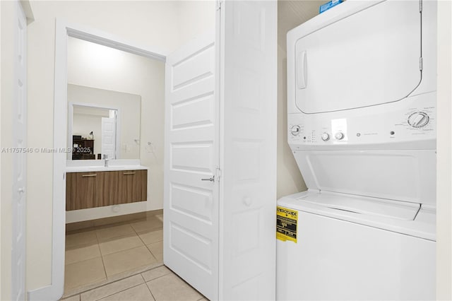 laundry area featuring laundry area, stacked washing maching and dryer, a sink, and light tile patterned flooring