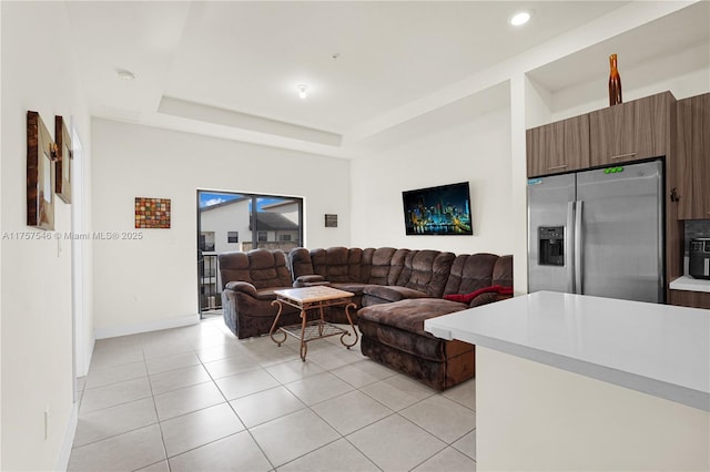 living room featuring light tile patterned floors, baseboards, a tray ceiling, and recessed lighting