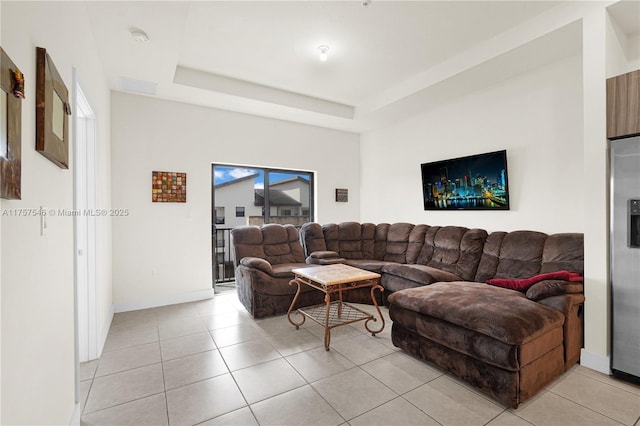 living area with a raised ceiling, baseboards, and light tile patterned floors