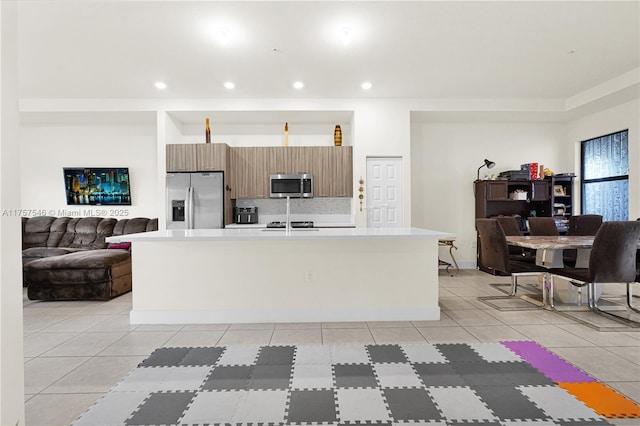 kitchen with an island with sink, appliances with stainless steel finishes, open floor plan, light countertops, and recessed lighting