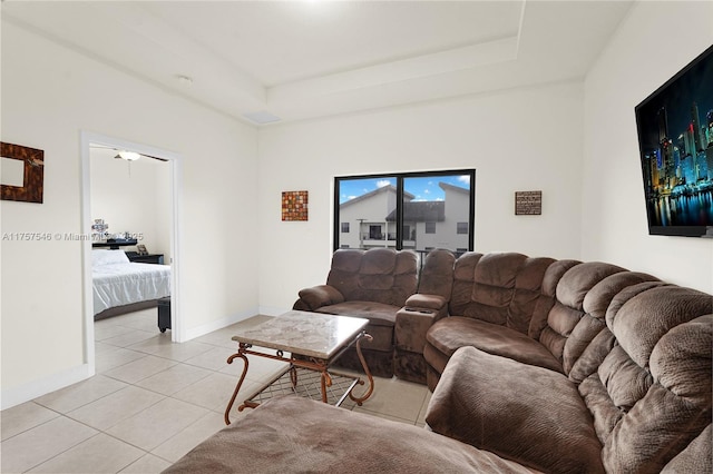 living area with a raised ceiling, baseboards, and light tile patterned floors