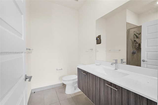 full bathroom featuring toilet, vanity, tiled shower, baseboards, and tile patterned floors