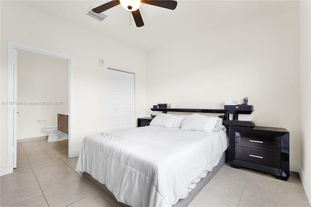 bedroom featuring ensuite bathroom, light tile patterned flooring, visible vents, and a ceiling fan