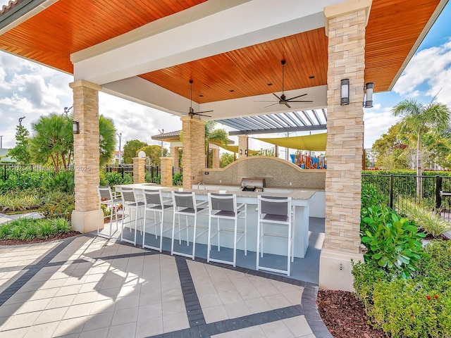 view of patio / terrace featuring outdoor wet bar, fence, area for grilling, and ceiling fan