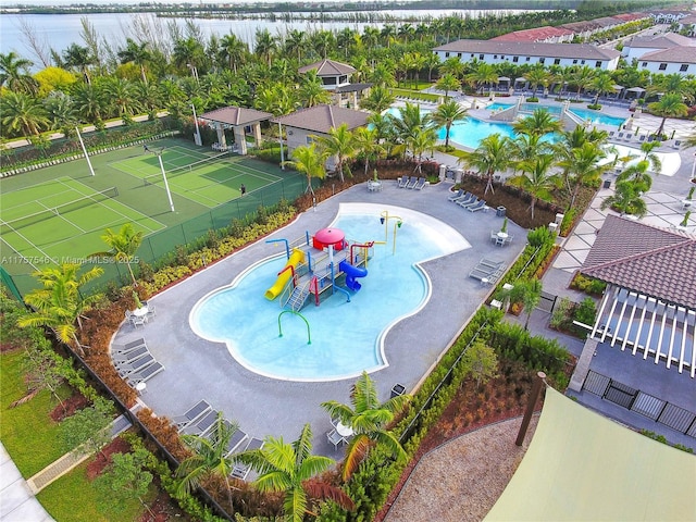 community pool with a water view, fence, and a water play area