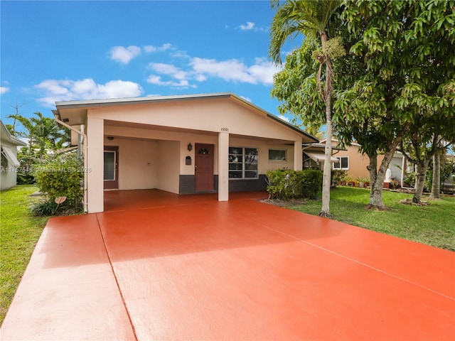 view of front of property featuring a carport, a front lawn, concrete driveway, and stucco siding