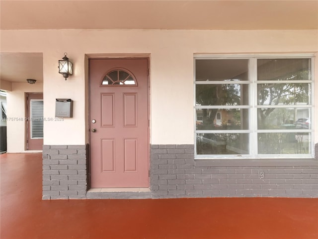 entrance to property featuring brick siding and stucco siding