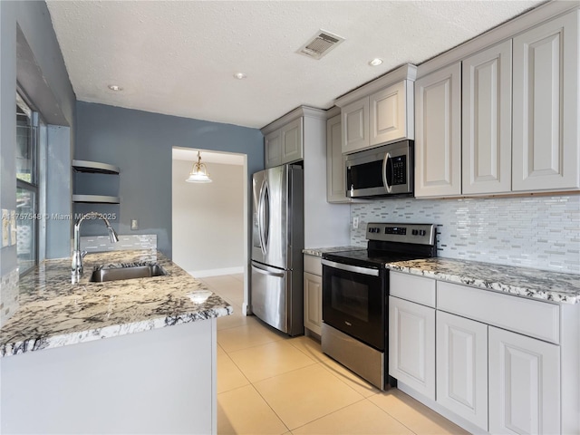 kitchen with light tile patterned floors, stainless steel appliances, backsplash, and a sink
