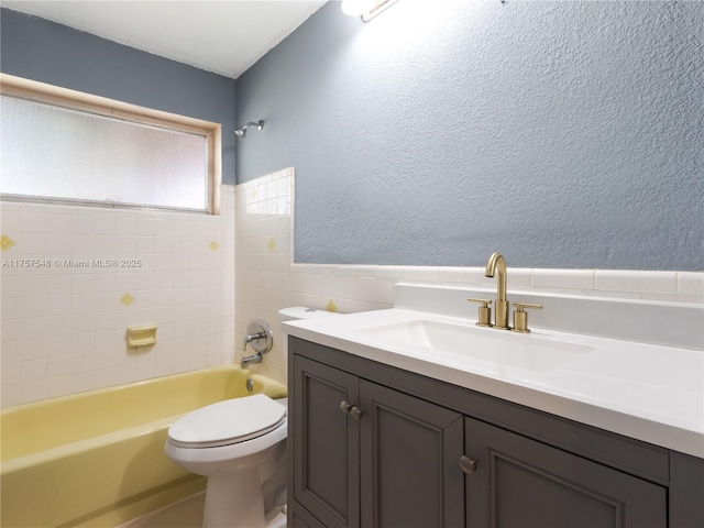 full bath featuring a textured wall, shower / washtub combination, vanity, and toilet