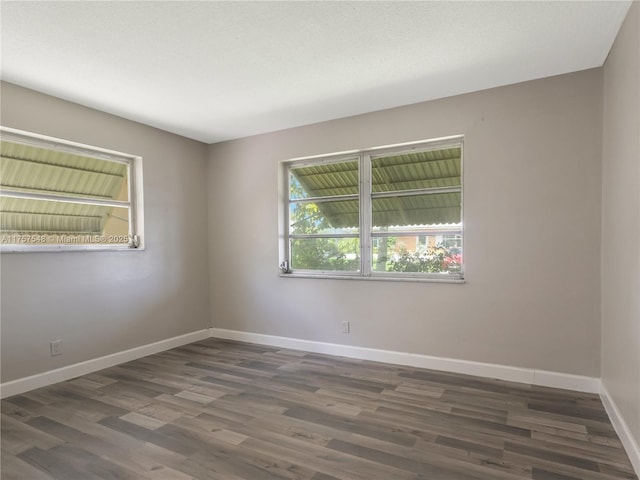 spare room with baseboards and wood finished floors