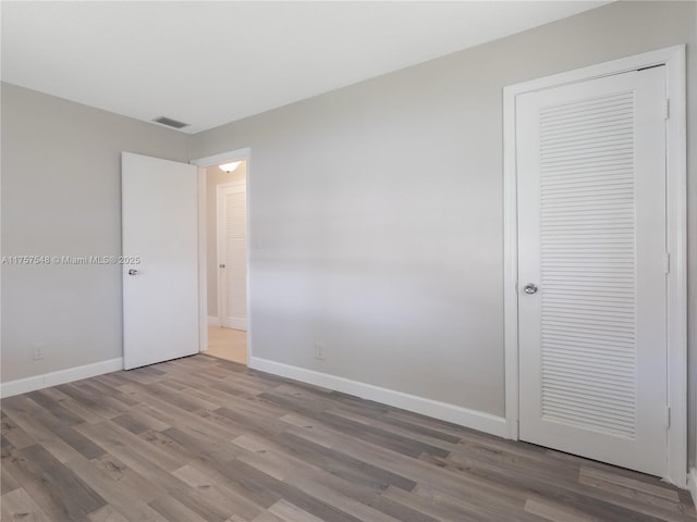 unfurnished bedroom featuring wood finished floors, visible vents, and baseboards