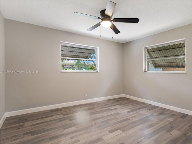 empty room with ceiling fan, wood finished floors, and baseboards