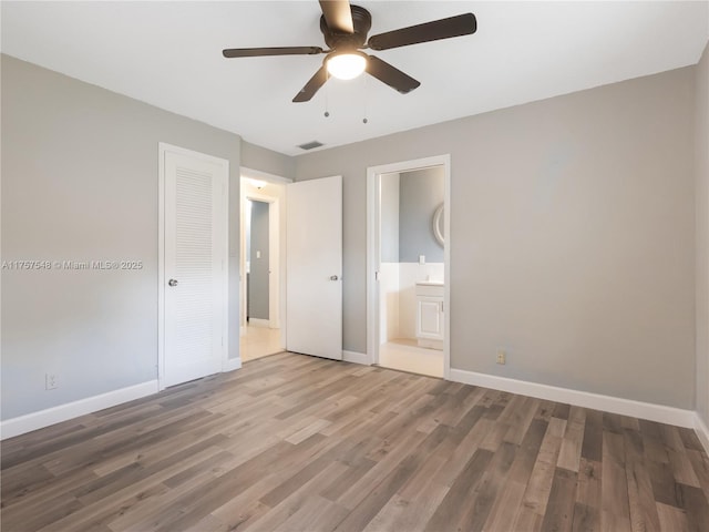 unfurnished bedroom with baseboards, visible vents, wood finished floors, and ensuite bathroom