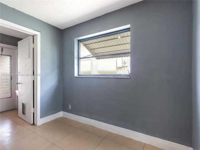 spare room featuring light tile patterned flooring and baseboards