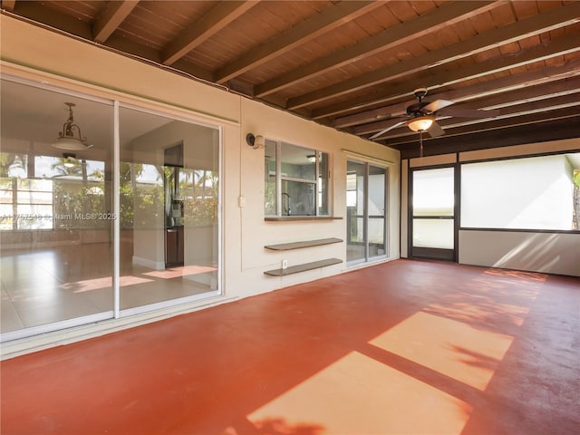 unfurnished sunroom featuring a ceiling fan, beam ceiling, and wooden ceiling
