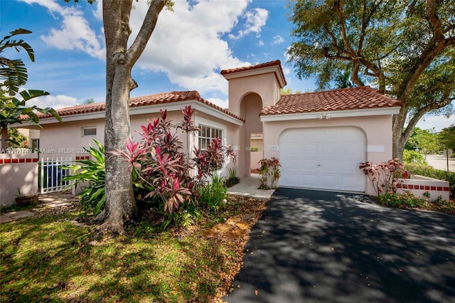 mediterranean / spanish home featuring a tile roof, driveway, an attached garage, and stucco siding